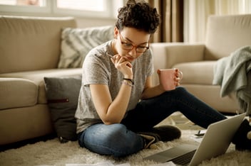 Woman sitting on the floor of her home working on laptop