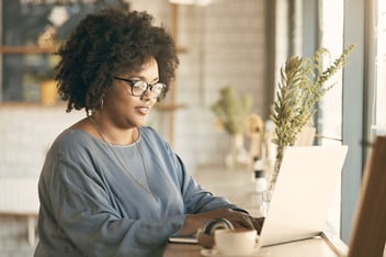 Woman working at laptop in cafe.