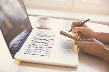 Woman working at laptop taking notes