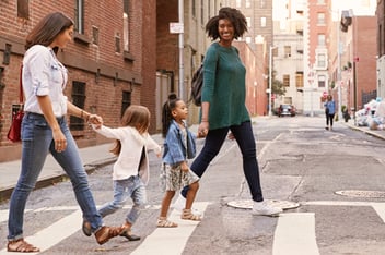 Two women walking in the city with their children