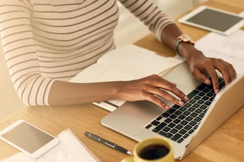 Woman typing on laptop in home office.