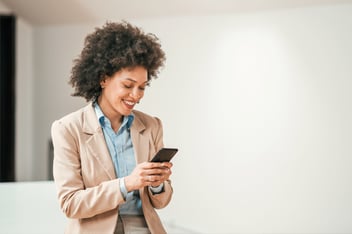 Woman in business suit on smartphone indoors