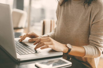 Close up of woman's hands typing on laptop
