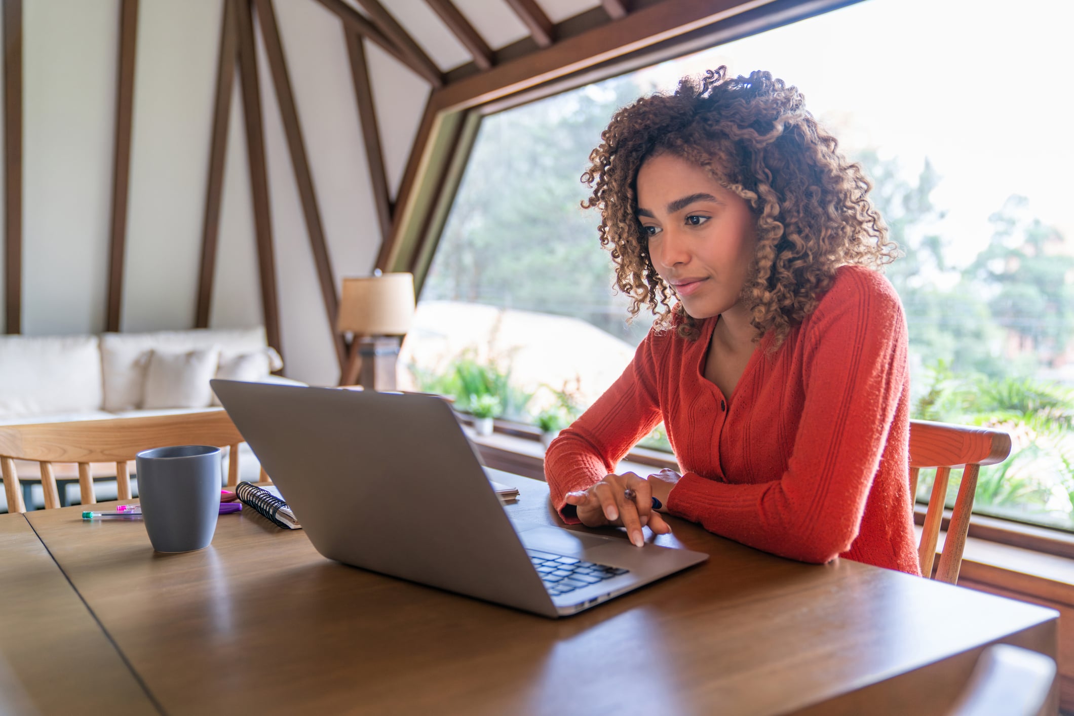 Woman in orange shirt using laptop